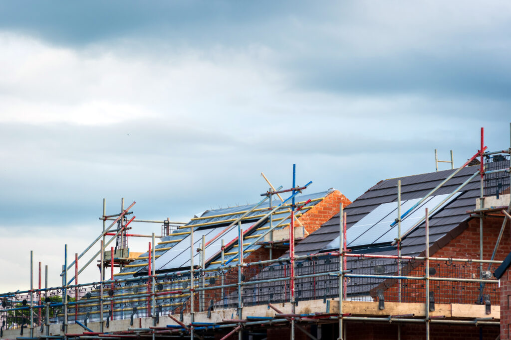 This is an image of solar panels being installed during the construction process of a row of homes. 
