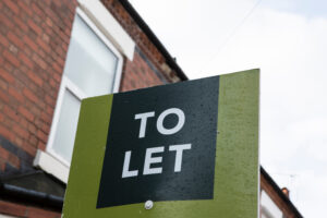 This is an image of the UK property rental market. There is a green and black sign with "TO LET" in white lettering.